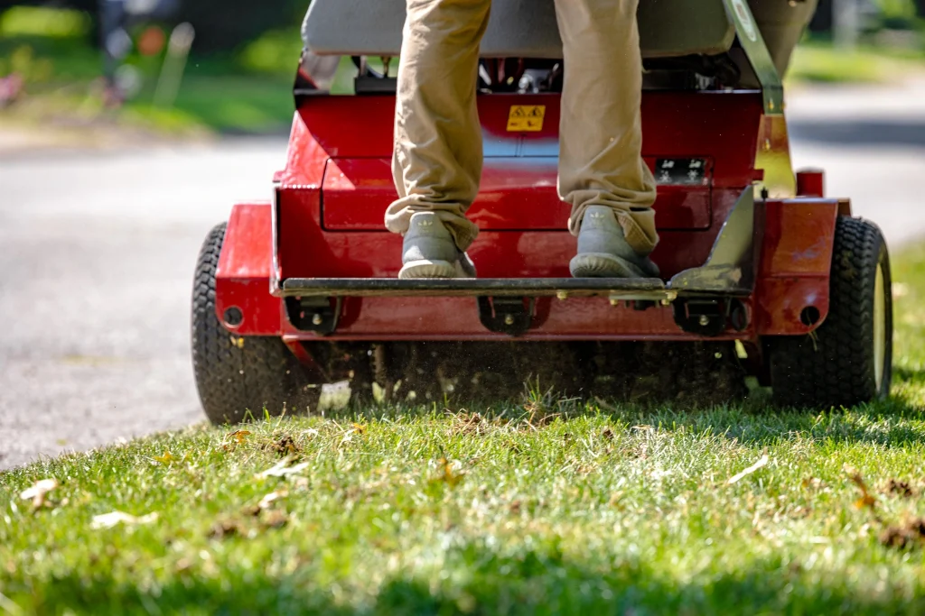 Lawn care professional using a ride-on core aerator to aerate a lawn for improved soil health and grass growth.